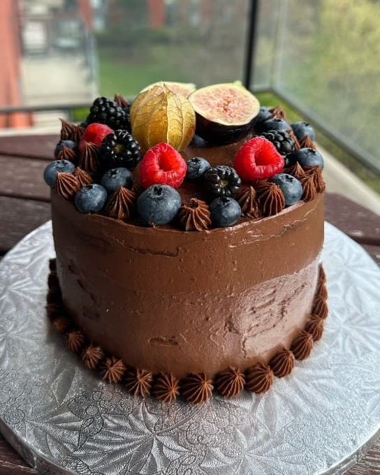 A chocolate cake decorated with berries and fig