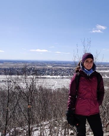 Paria on a snowy overlook in a magenta jacket